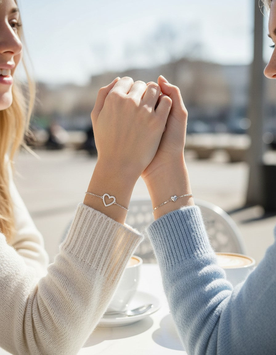 Best friends holding hands wearing the silver open-heart and solid-heart bracelets