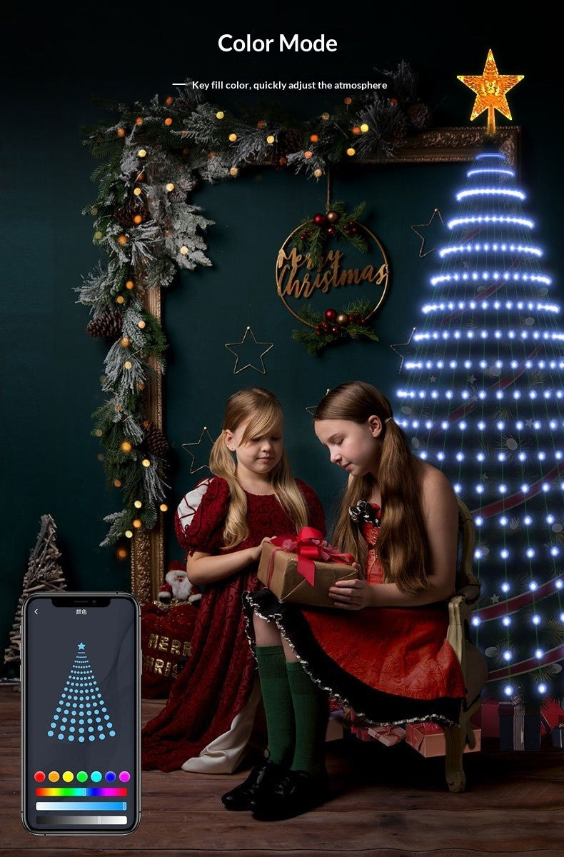 Two girls opening a gift beside tree lights set to a single cool white color from the app